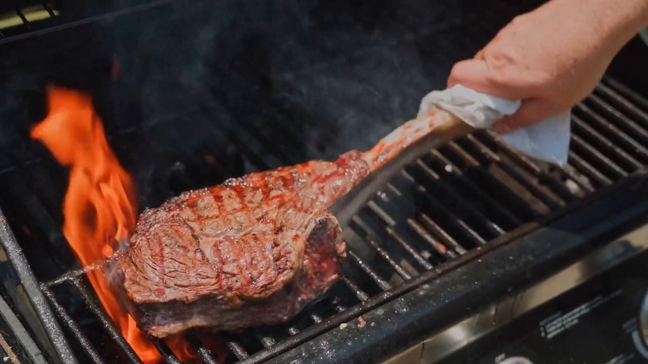 Tomahawk asado en parrilla con llamas vivas